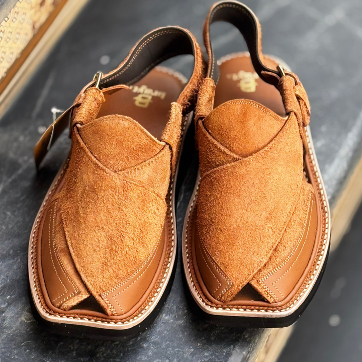 Pair of brown leather sandals on a dark surface
